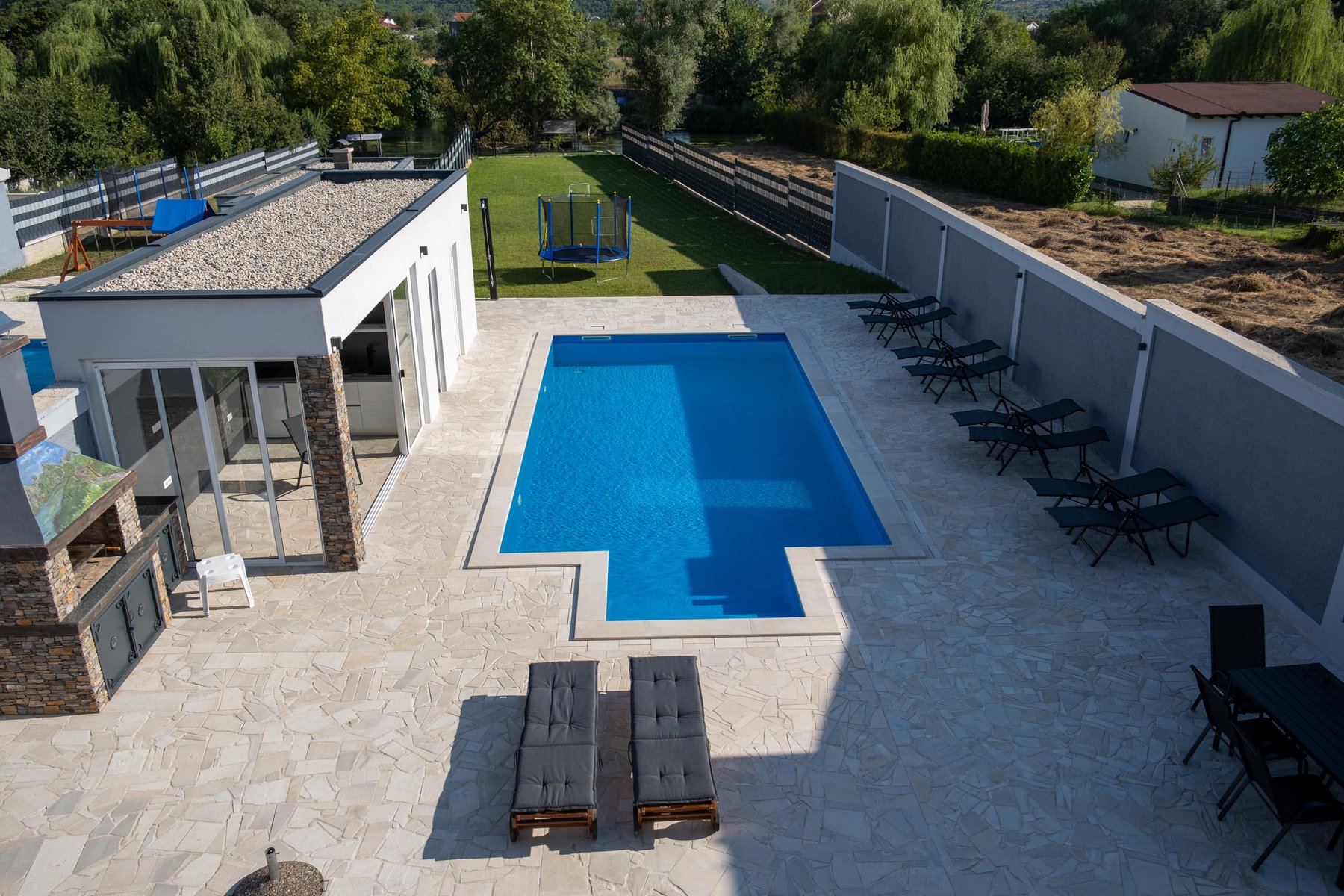 Aerial view of Villa Verona's private pool, terrace and green lawn by the river in Blagaj, near Mostar